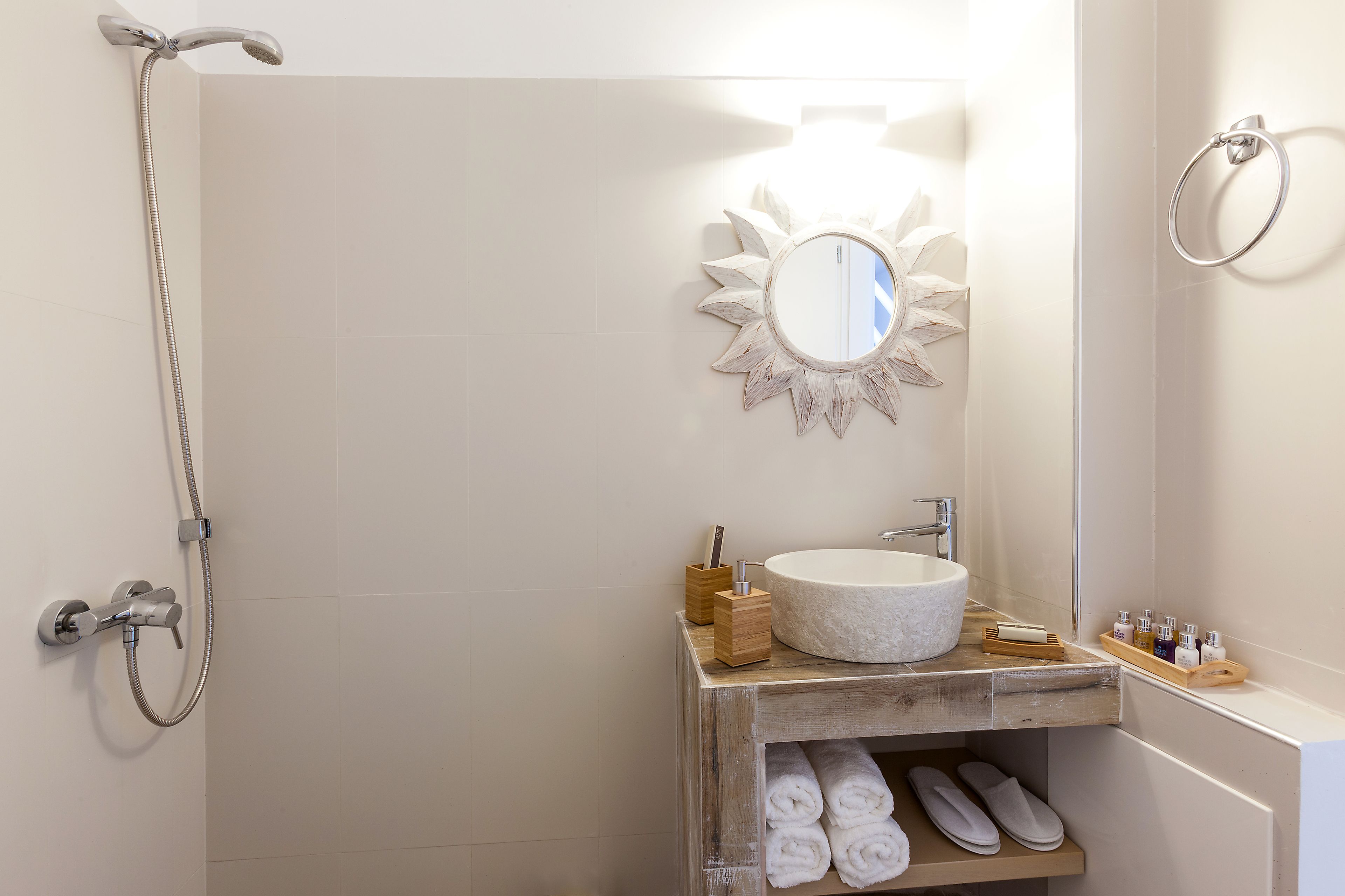 A bathroom with a shower, a sink, a mirror, and a towel rack.