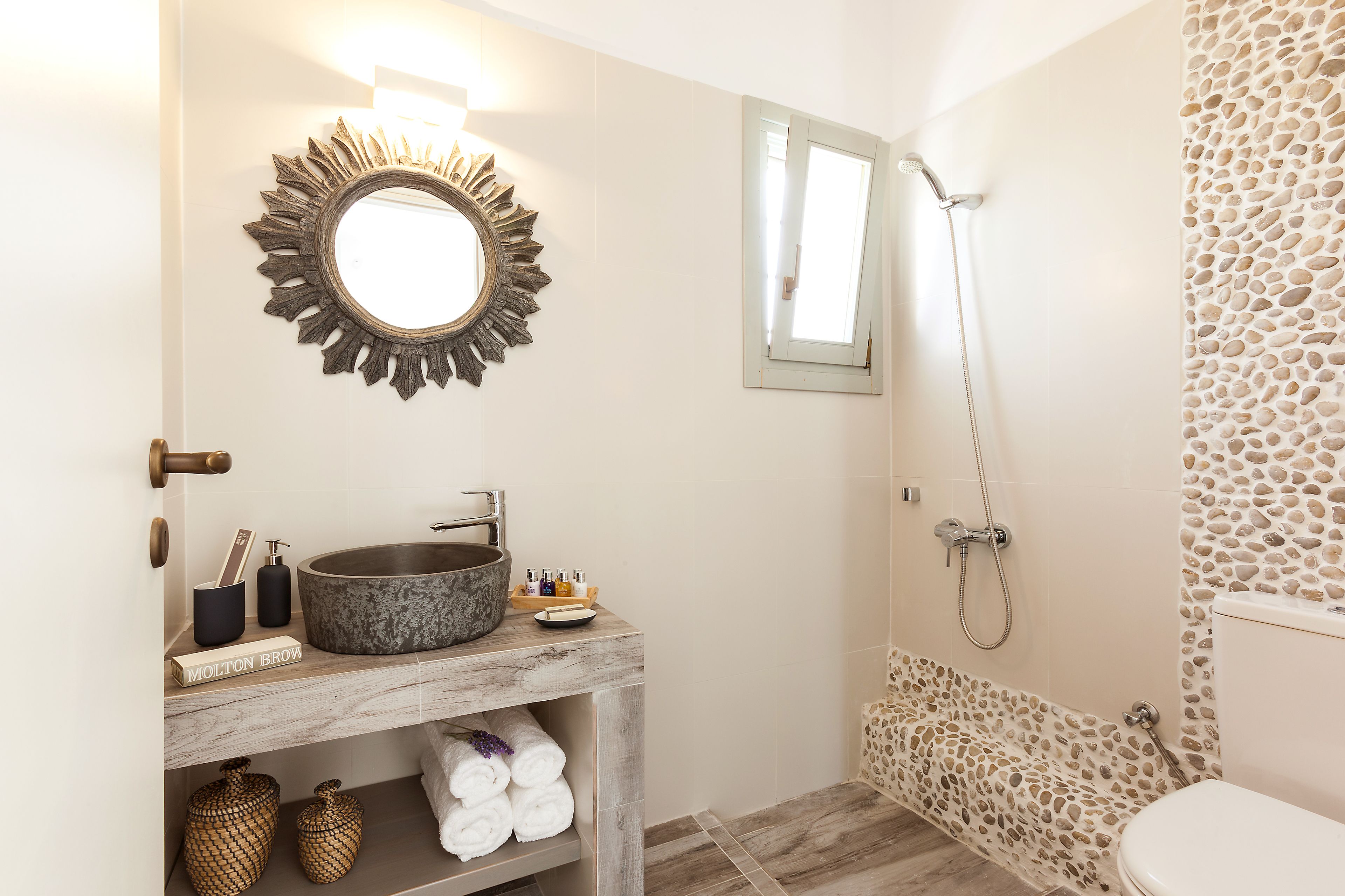 Un baño con lavamanos de piedra, espejo, ducha y retrete.