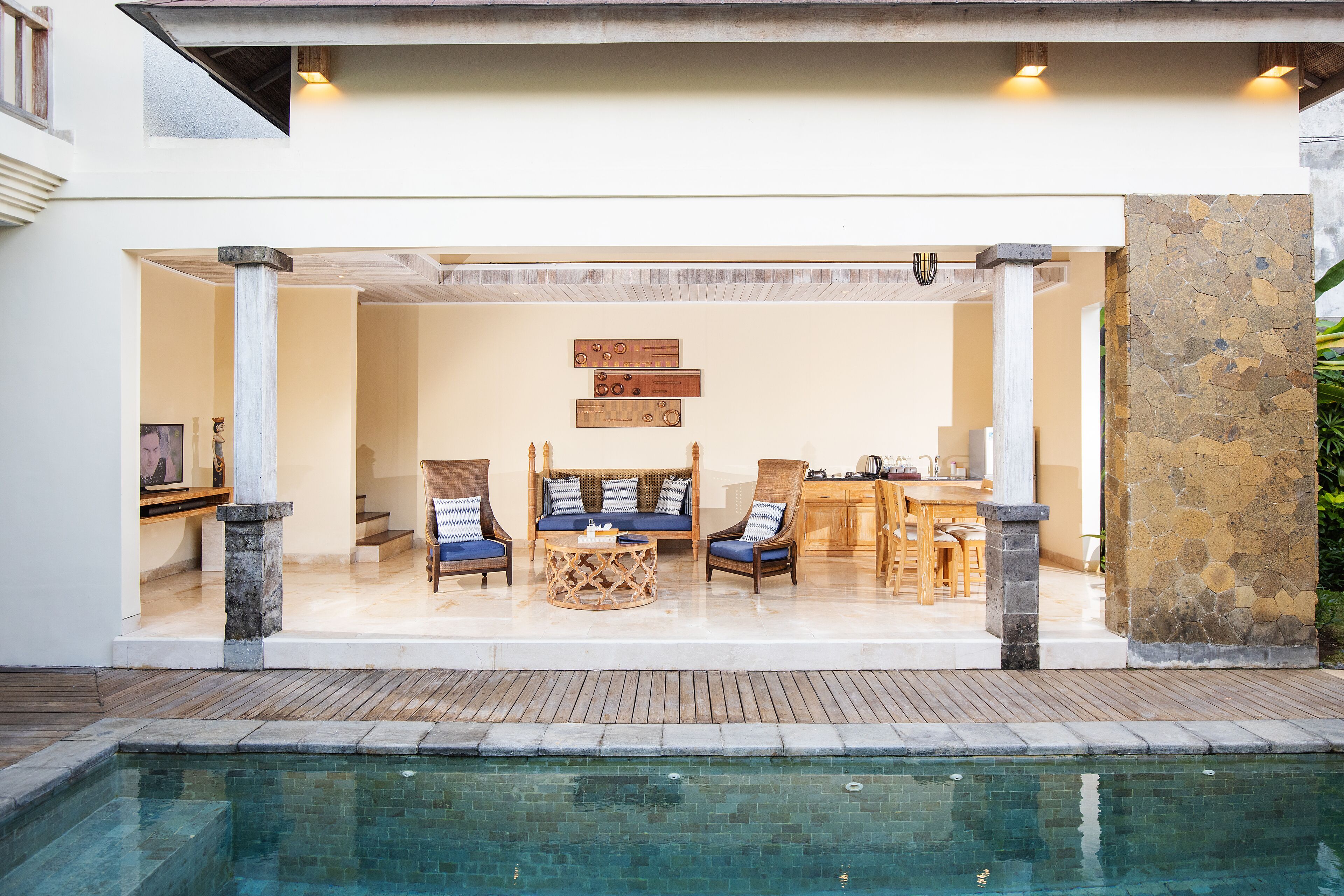 A poolside area with a seating arrangement, a stone wall, and a view of the pool.