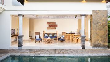 A poolside area with a seating arrangement, a stone wall, and a view of the pool.