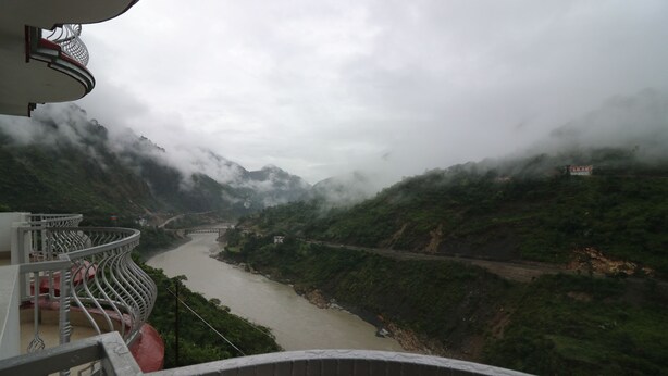 A river valley with a bridge, surrounded by mountains and greenery. - Hotel Mandakini (Jakholi)