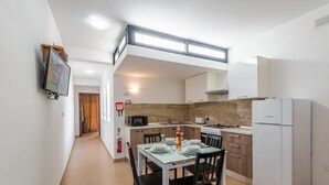 Una cocina compacta con comedor, microondas, estufa y refrigerador.