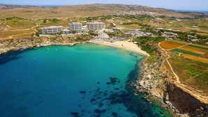 Vista aérea de una zona costera con un complejo hotelero, una playa y campos circundantes.