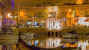 Una orilla tranquila con barcos amarrados, un llamativo letrero 'LION' y un edificio con fachada clásica.