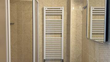 A modern bathroom with a glass shower enclosure, a bidet, and a sink with a mirror.