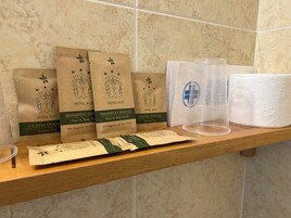 Estante con artículos de aseo de hotel, incluyendo gorros de ducha, champú y otro gorro de ducha.