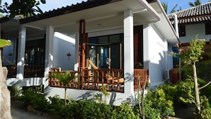 A modern house with a covered porch, large windows, and a garden. - Benjamin Hut (Ko Pha-ngan)