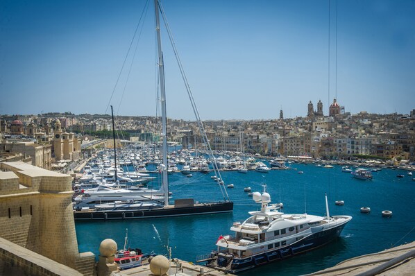 A marina with multiple boats docked, a prominent sailboat, and a cityscape in the background. - Blue Harbour 2 by Getaways Malta (St. Paul's Bay)