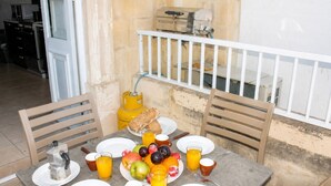 A breakfast table with plates, cups, a coffee pot, a gas cylinder, and a fruit bowl. - Blue Harbour 1 by Getaways Malta (St. Paul's Bay)