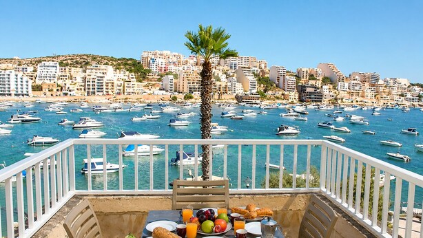 A balcony with a table set for breakfast overlooking a marina with numerous boats. - Blue Harbour 1 by Getaways Malta (St. Paul's Bay)