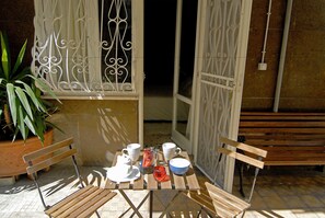 An outdoor dining area with a wooden table set for two, surrounded by metal chairs. - Tiburtina Garden (Rome)