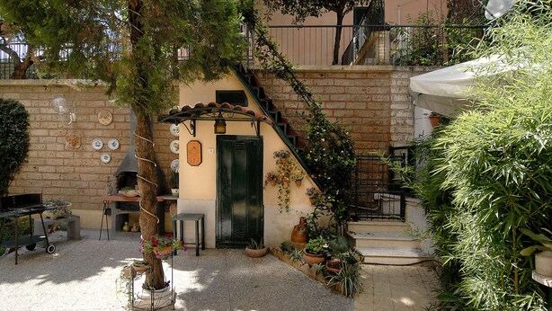 Une cour avec un mur en briques, une porte en bois et des plantes en pot.
