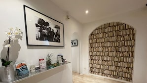 Un espace d’accueil comprenant une photographie encadrée, une vitrine exposant divers objets et une bibliothèque remplie de livres.