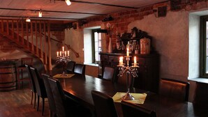 A dining area with a long wooden table, chairs, and candle-lit candelabras. A staircase is visible in the background. - Östanskär Jakt & Konferens (Indal)