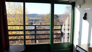 A room with a large window offering a view of autumn trees and hills. - Östanskär Jakt & Konferens (Indal)