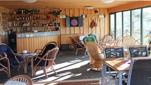A rustic bar area with wooden walls, wicker furniture, and a dartboard. - Östanskär Jakt & Konferens (Indal)
