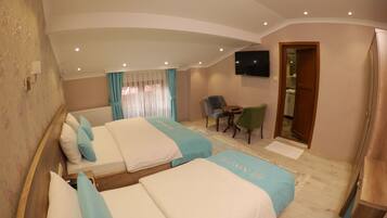 Quarto de hotel com duas camas, uma televisão, uma mesinha e uma cadeira.