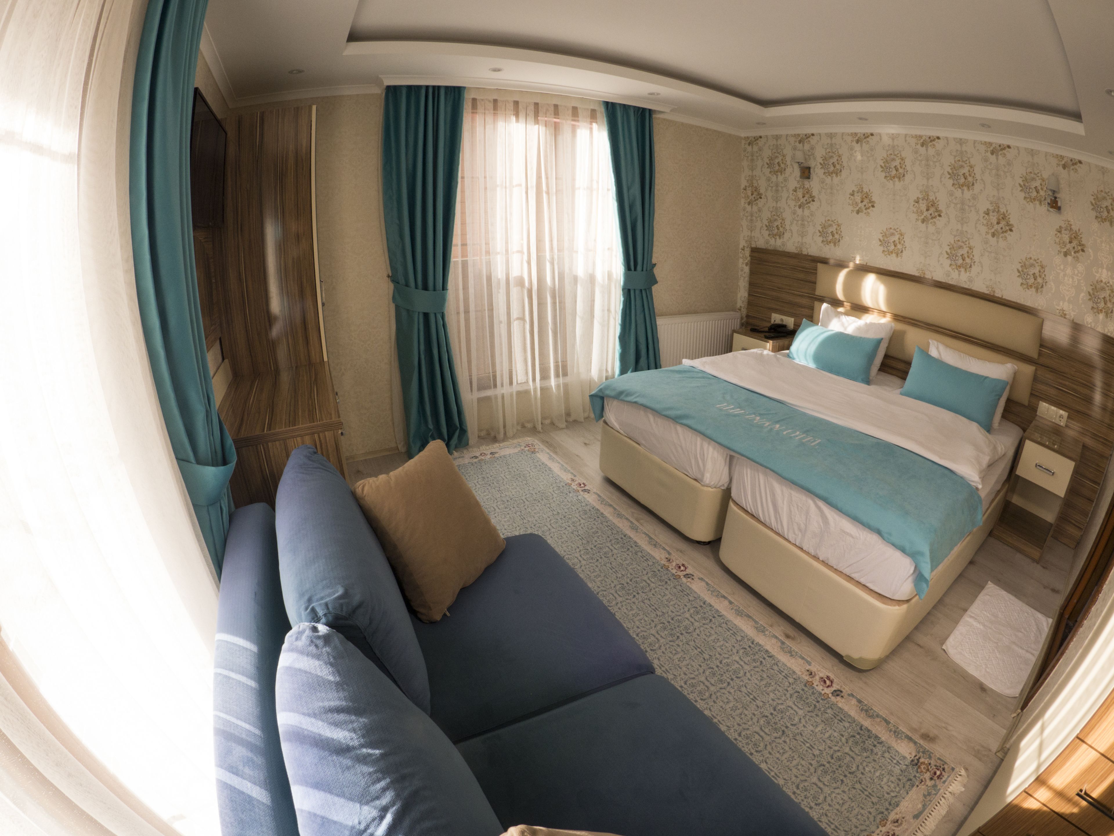 A bedroom with a bed, a sofa, and a window with curtains.