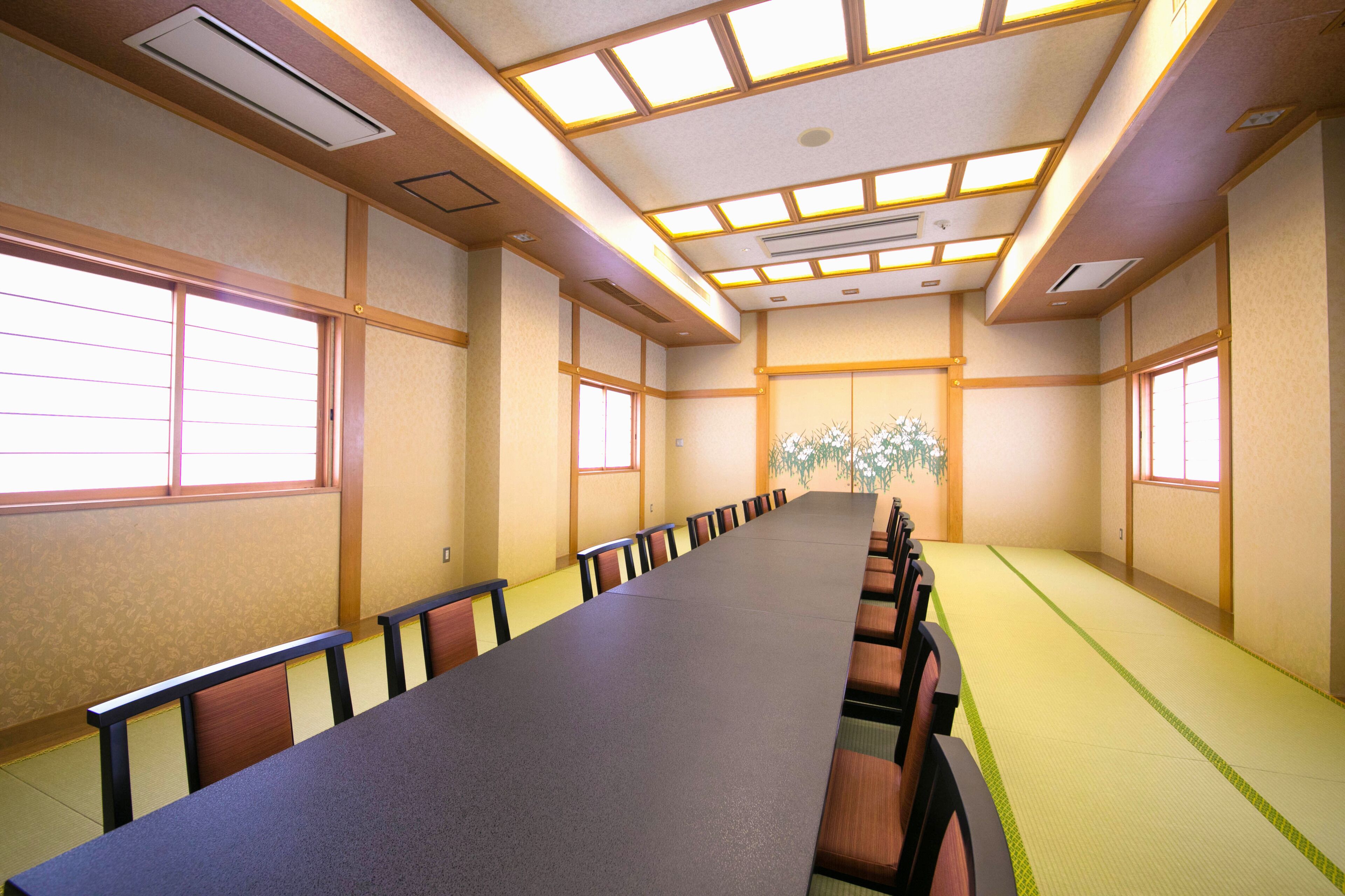 Ett konferensrum med ett långt bord, stolar och ett traditionellt japanskt tak med takfönster.