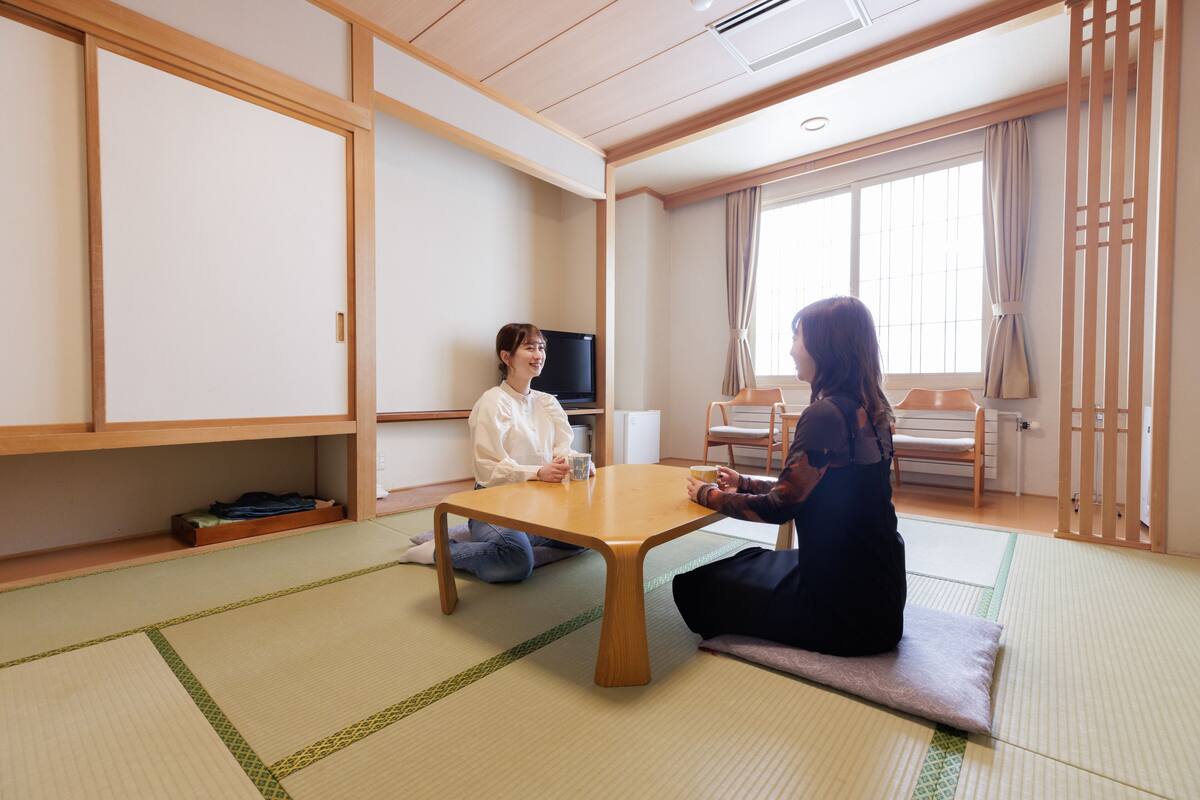 Une pièce de style japonais traditionnel, avec un sol recouvert de tatamis, une basse table en bois et des portes coulissantes.