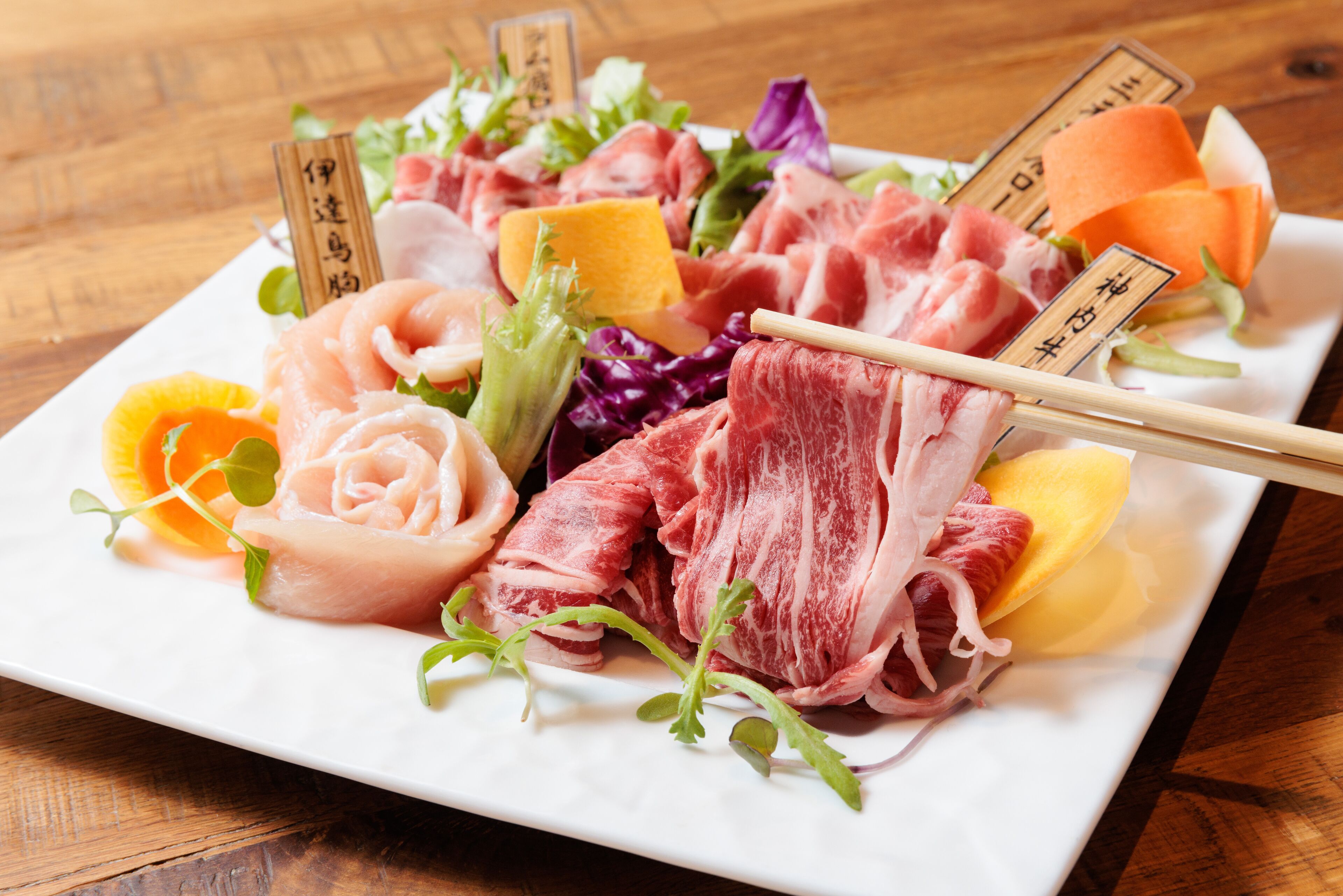 A plate of assorted meats and vegetables on a wooden table.