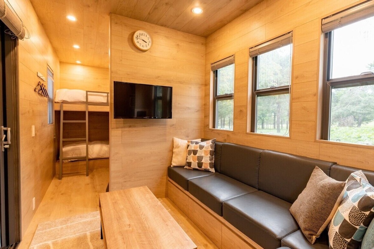 A cozy cabin interior with a wooden interior, a sofa, a TV, and a bunk bed.