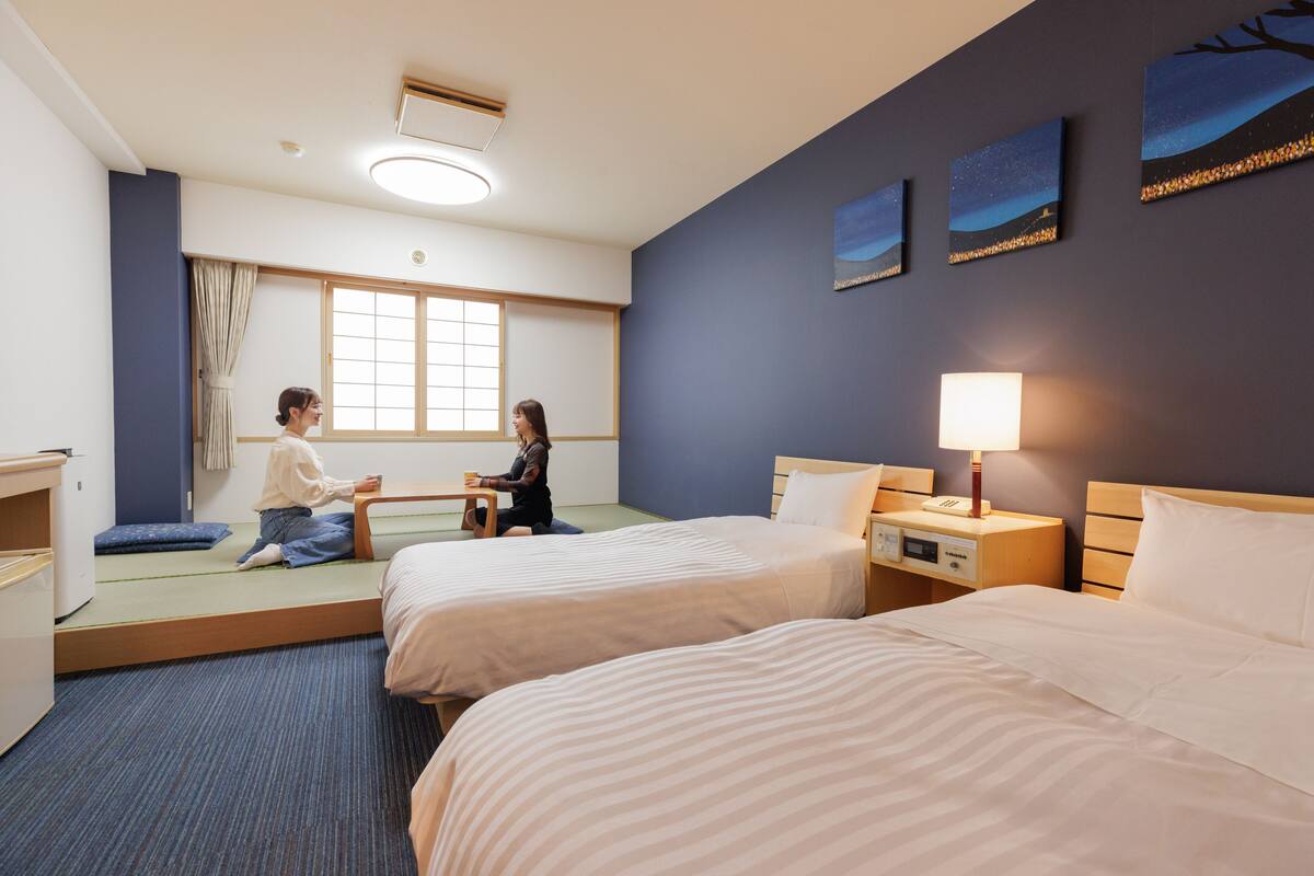 Une chambre d’hôtel avec deux lits, un bureau et une fenêtre.