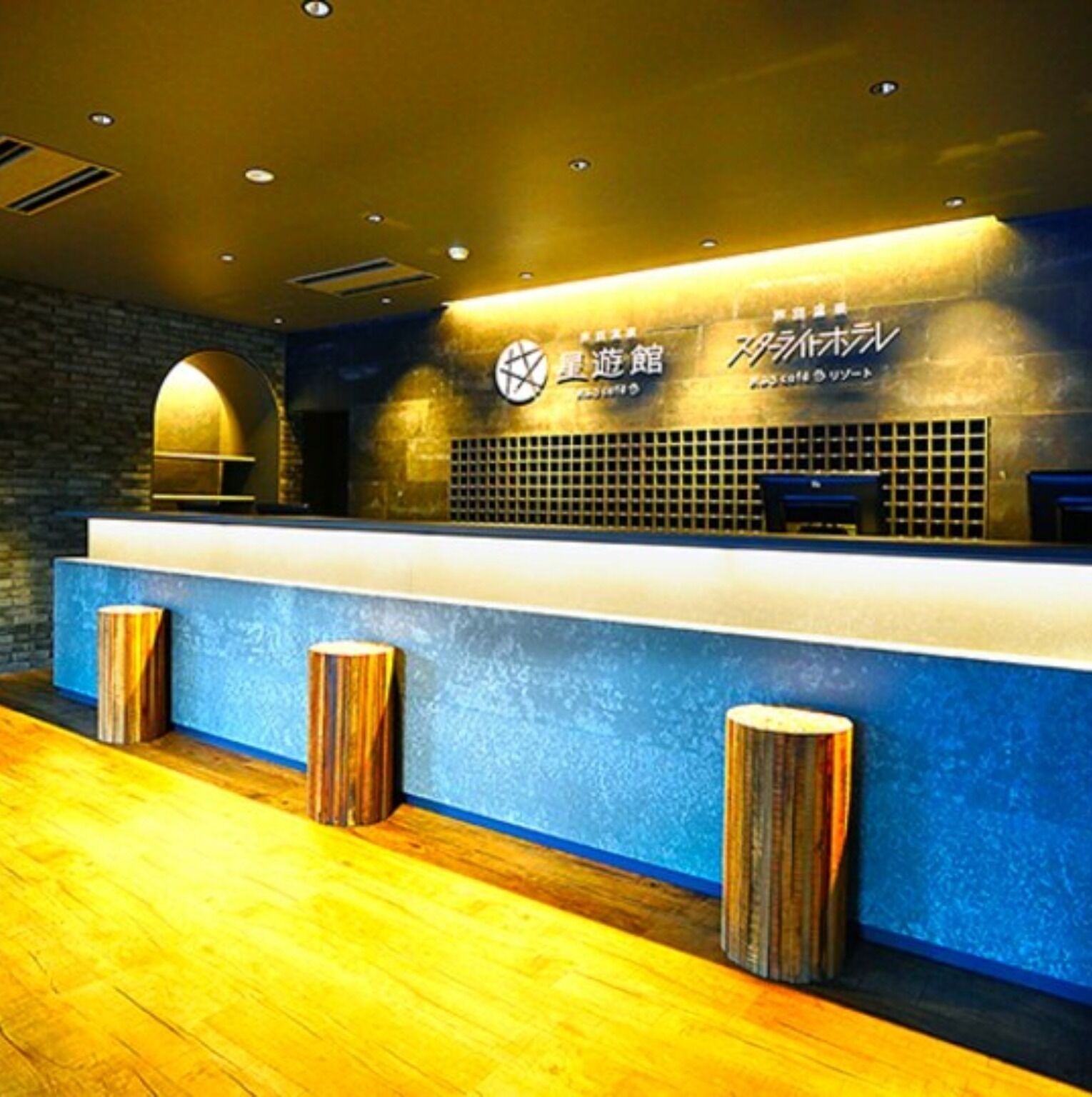 A reception area with a blue counter, wooden stools, and a clock.