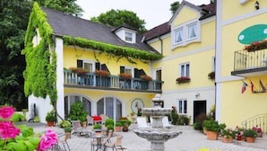 A courtyard with a fountain, potted plants, and outdoor seating. - Hotel Schlossgasthof Artstetten (Artstetten)