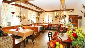 A cozy dining area with wooden benches and tables, decorated with flowers and fruit baskets. - Hotel Schlossgasthof Artstetten (Artstetten)