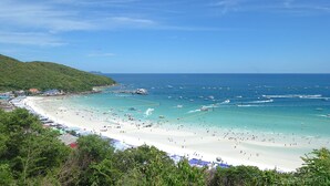 Una playa con aguas turquesas cristalinas, una orilla de arena y barcos.