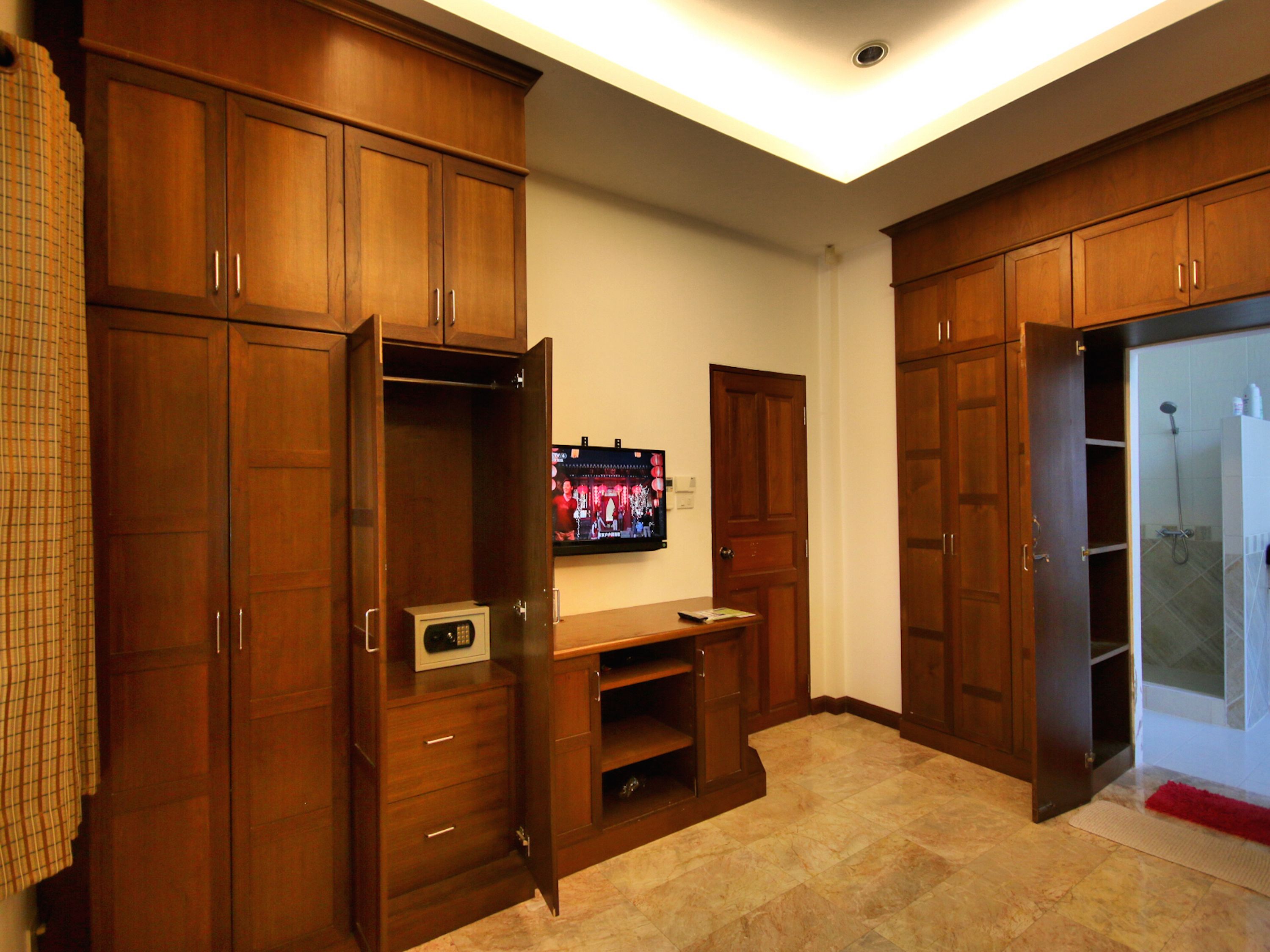 A room with wooden cabinets, a television, and a shower area.