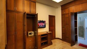 A room with wooden cabinets, a television, and a shower area.