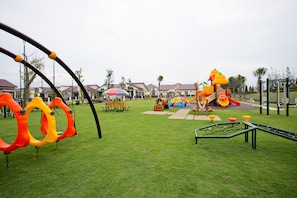 Ein Spielplatz mit Schaukeln, Rutschen und einer Kletterkonstruktion.
