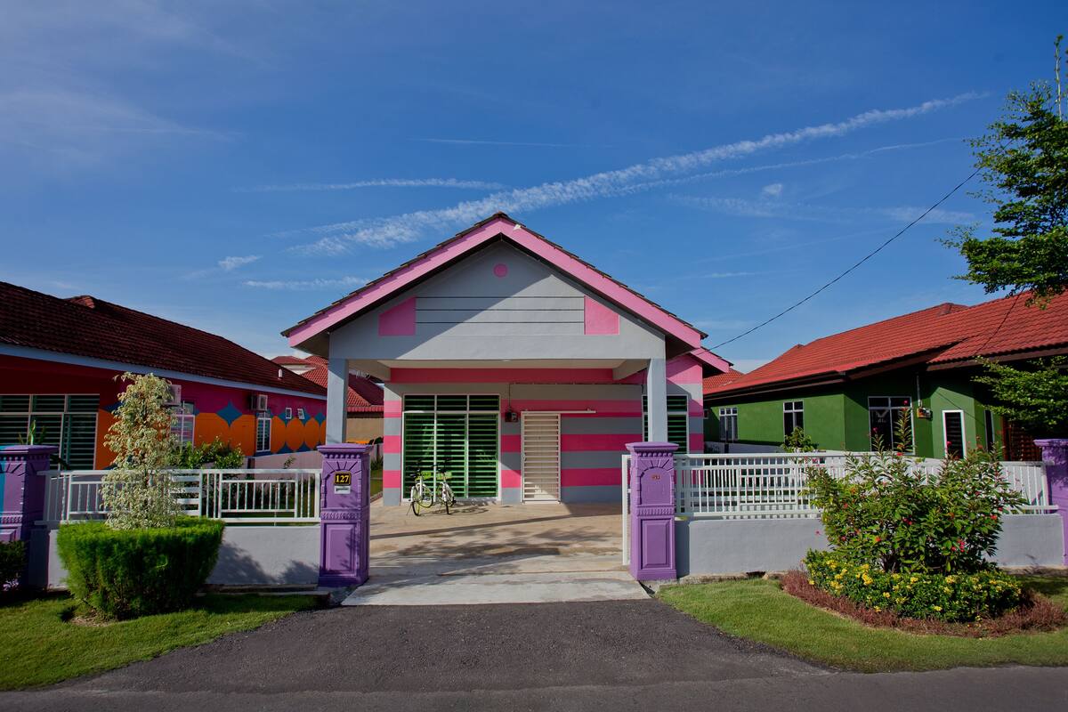 A colorful building with a central entrance, a bicycle parked outside, and a well-maintained lawn.