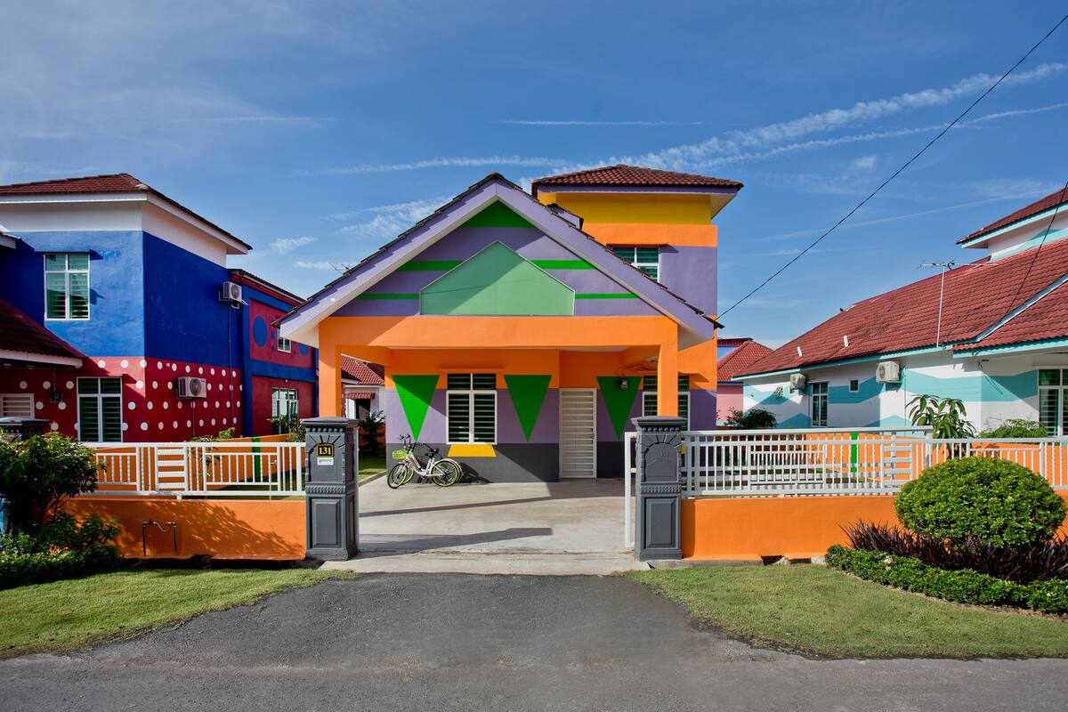 A colorful house with a front porch, a bicycle, and a well-maintained lawn.