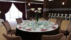 Una mesa redonda dispuesta para una reunión, con botellas de agua, vasos y un jarrón de flores.