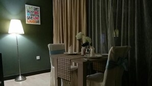 Un comedor con una mesa lista para dos personas, una lámpara y un cartel en la pared.