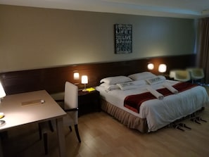 A hotel room with a neatly made bed, a bedside table with a lamp, a chair, and a wall with motivational quotes. - Temu Primula (Kampong Raja)