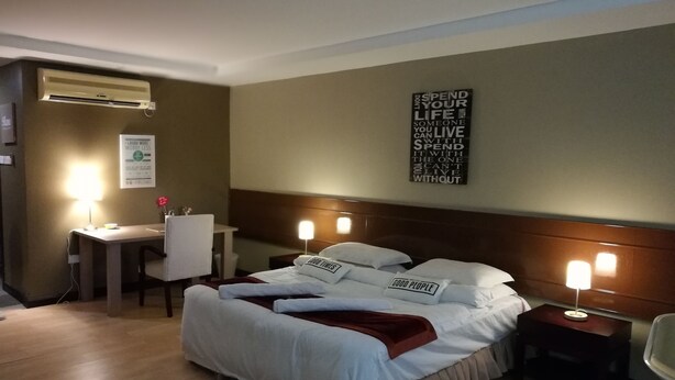Una habitación de hotel con cama, mesitas de noche, escritorio y silla.