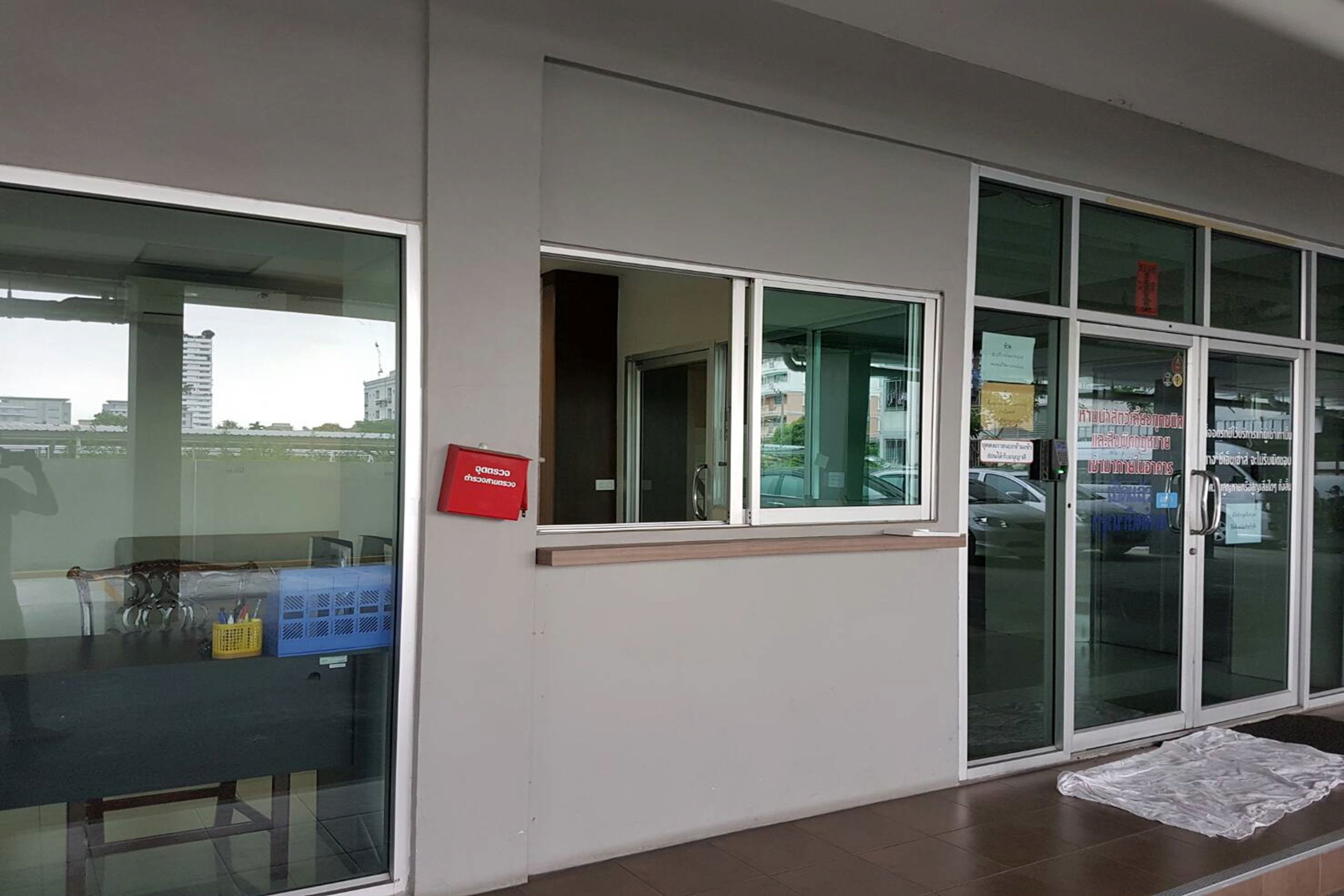 A building exterior with large windows, a door with glass panels, and a red sign on the wall.