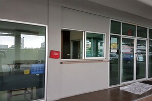 A building exterior with large windows, a door with glass panels, and a red sign on the wall.