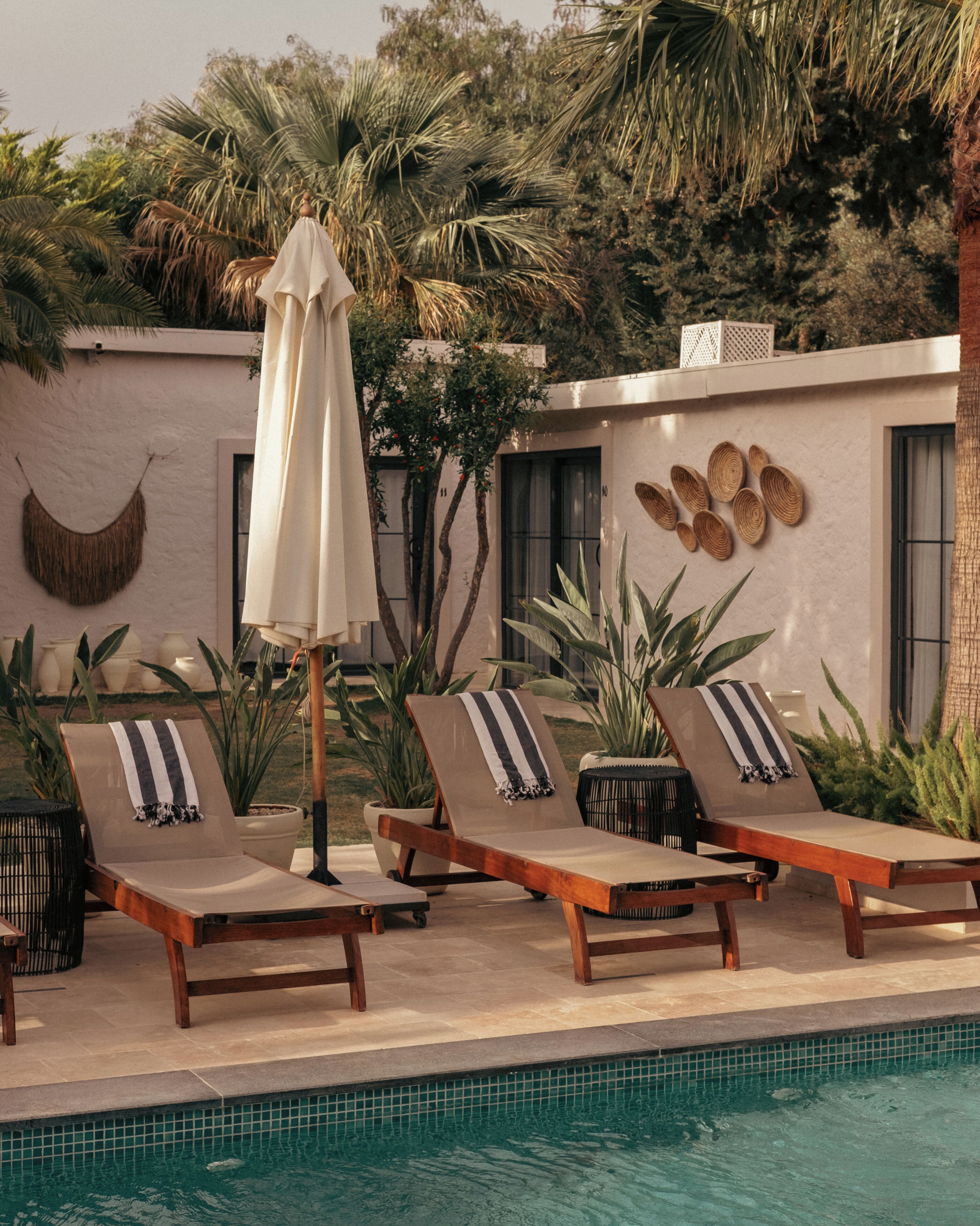 A poolside area with lounge chairs, a white umbrella, and decorative wall art.