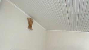 Une chambre à coucher avec un lit, des murs blancs, une tête de lit en bois et un plafond en pente.