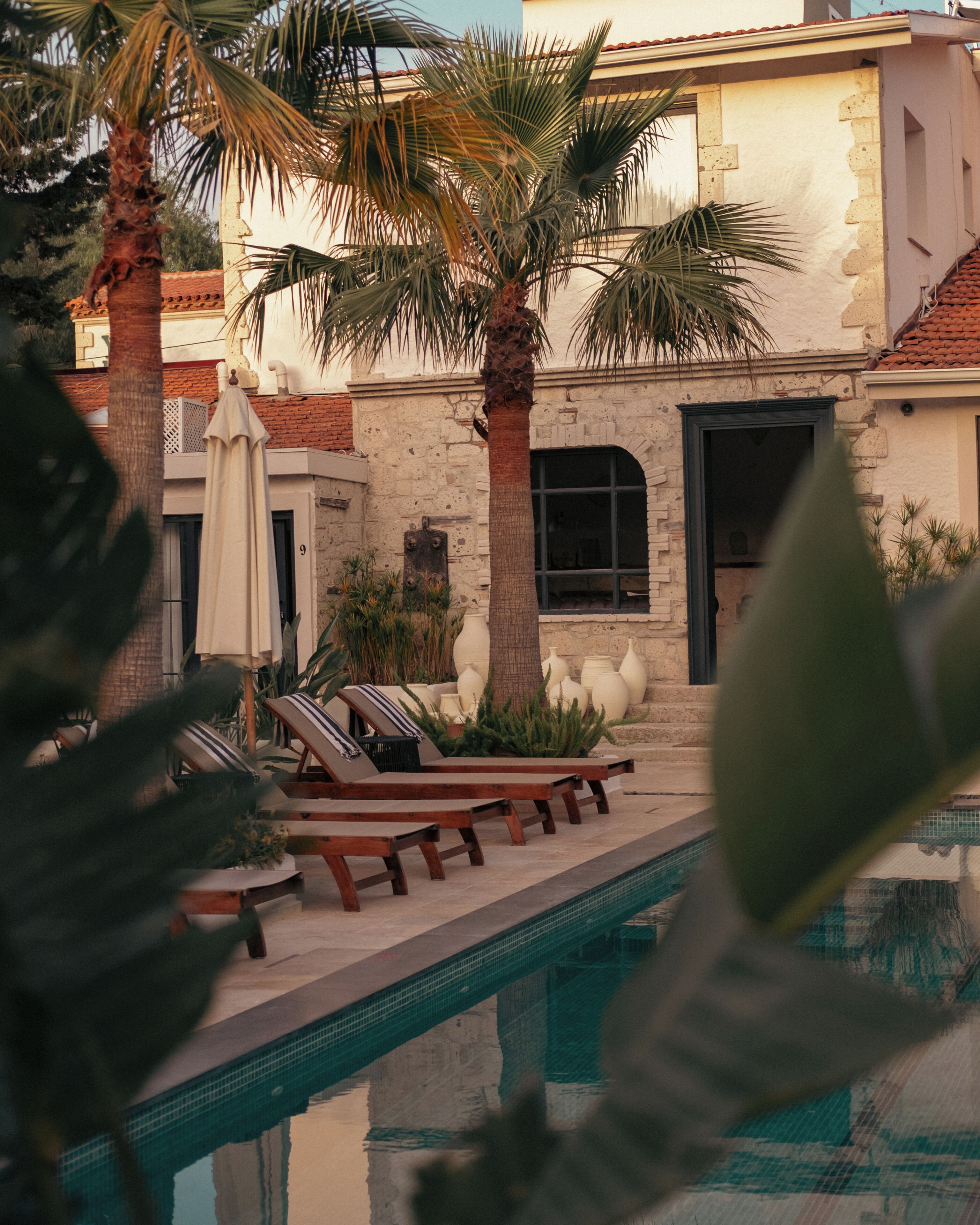 A poolside area with lounge chairs and a building with a stone facade.