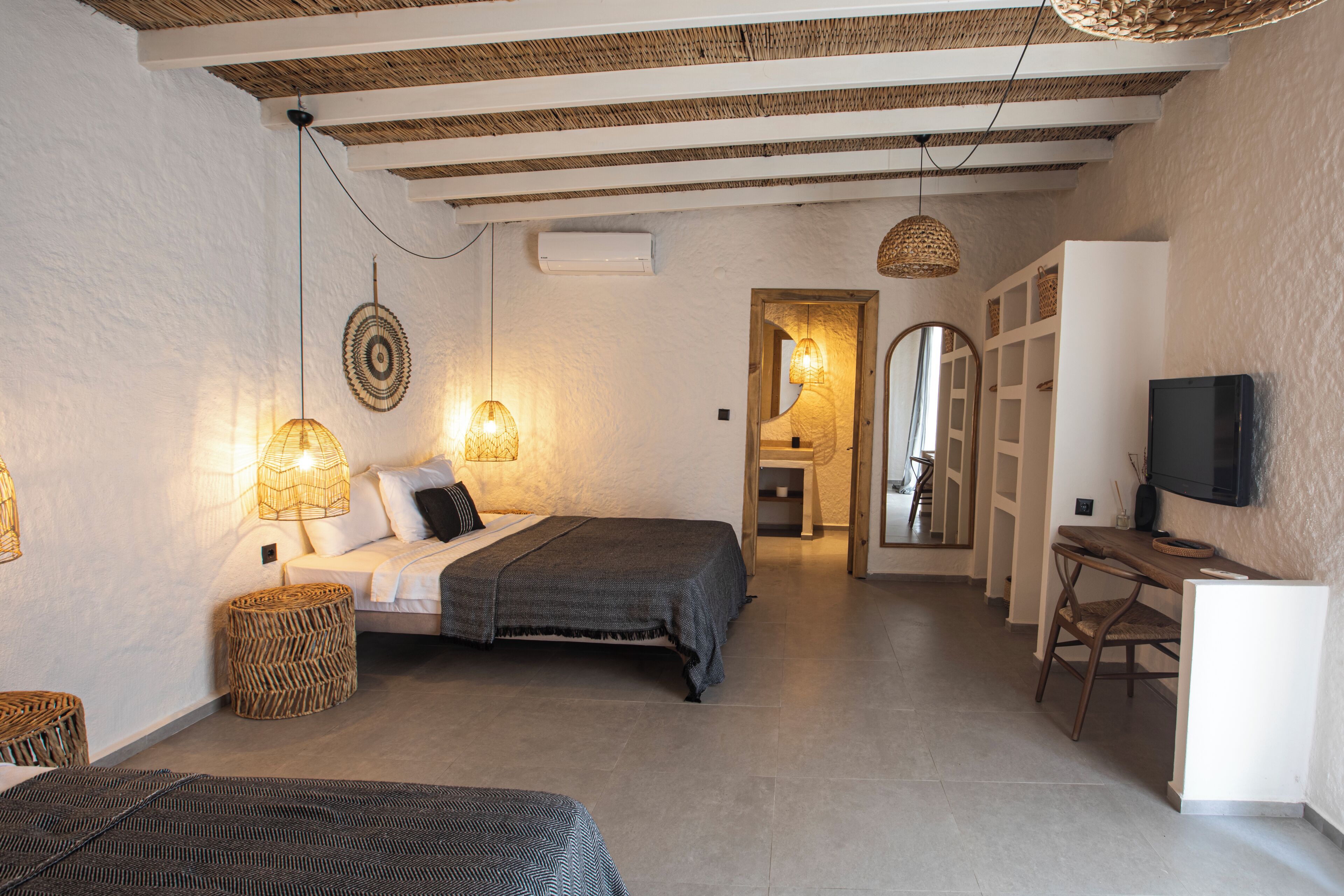 Ein Schlafzimmer mit einem Bett, Nachttischlampen, einem Fernseher und einer kleinen Schreibtischzeile.
