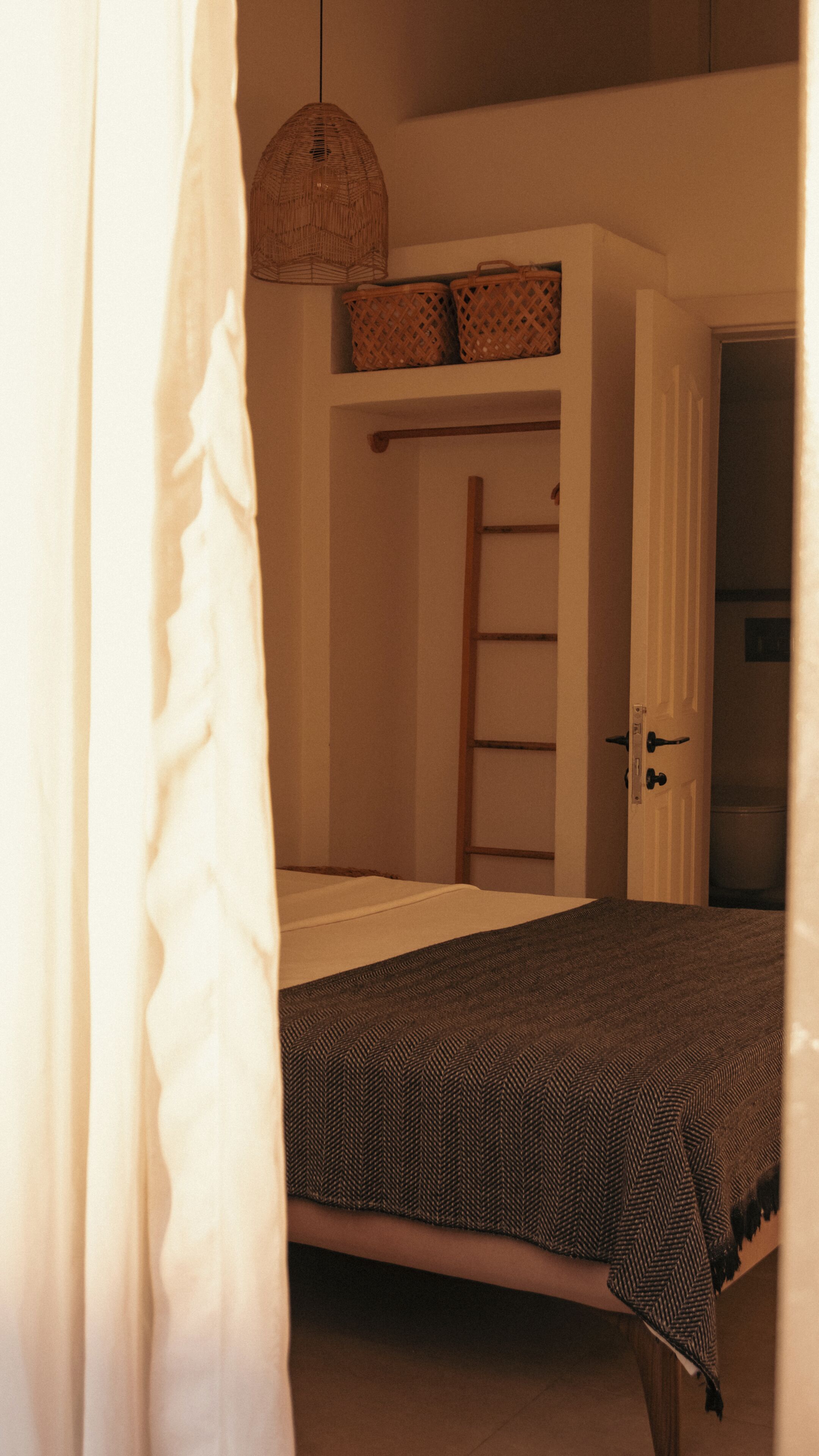 A bedroom with a bed, a wardrobe, a hanging basket, and a door.