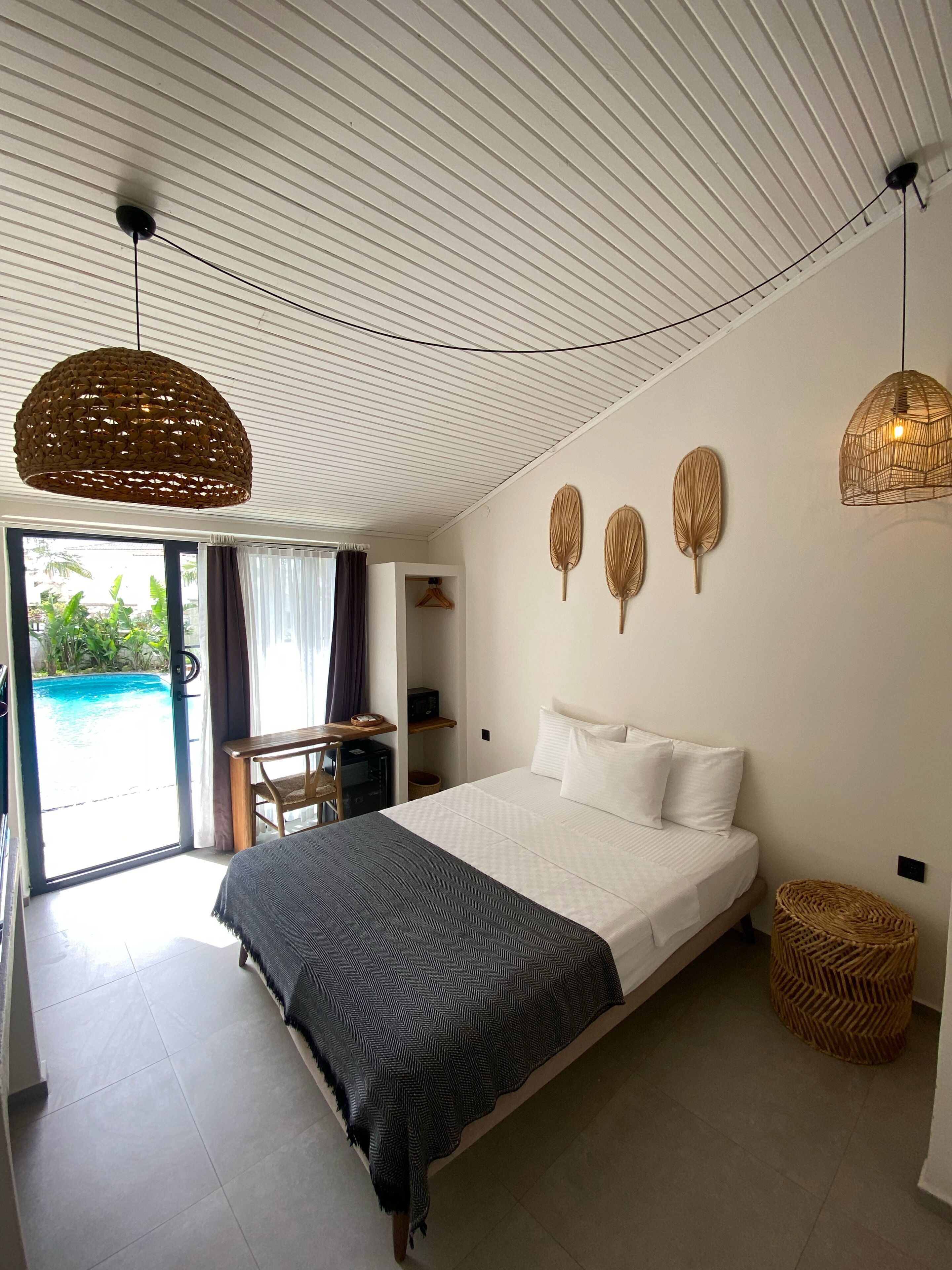 Ein Schlafzimmer mit Bett, Schreibtisch und Blick auf einen Außenpool.