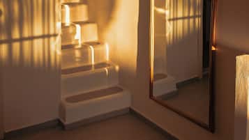 Una scala con uno specchio che riflette la stanza, un tappeto sul pavimento e una parete illuminata da una fonte di luce che proietta ombre.
