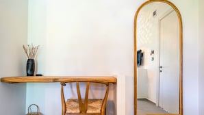 Une pièce comprenant un banc en bois, un panier tressé, un miroir fixé au mur et une porte.